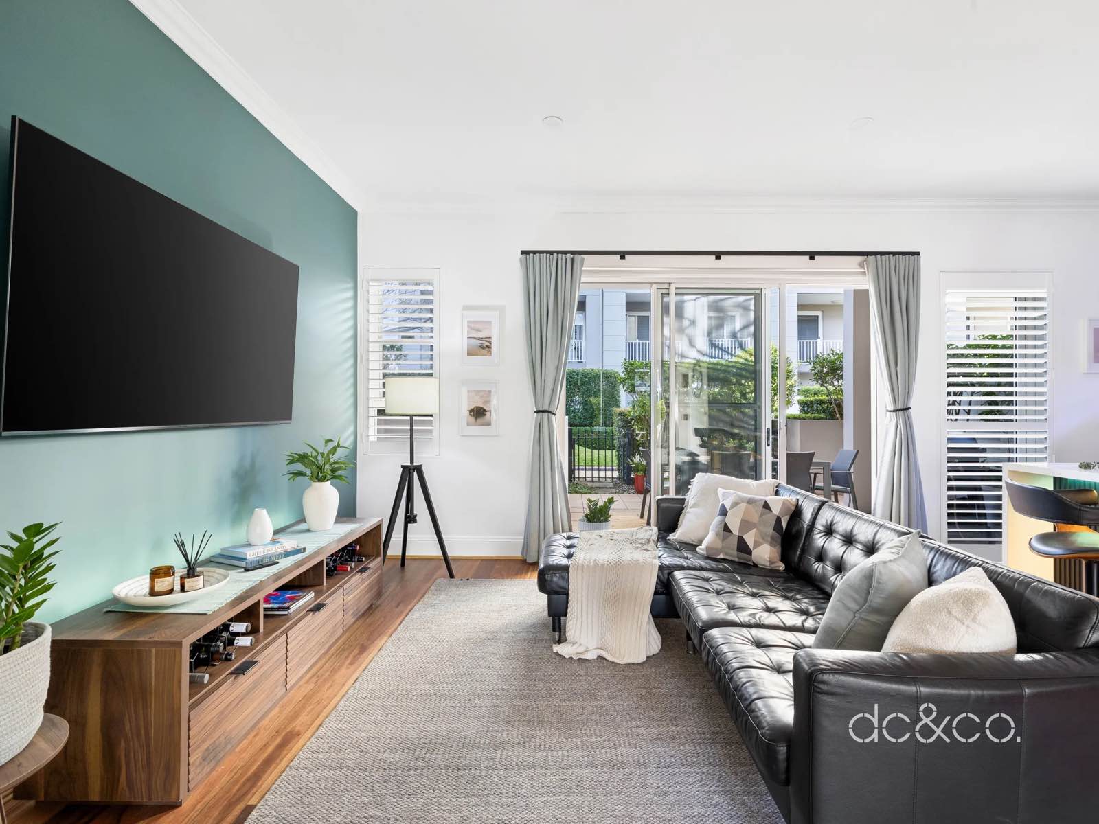 The living room looking out through sliding doors to the covered patio and hedged courtyard beyond